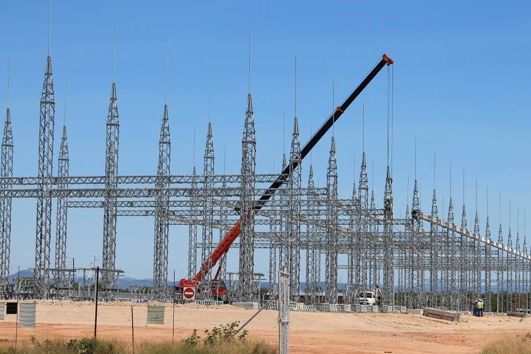 Rows of substation gantries and lightning masts with a crane working on the busbar structures